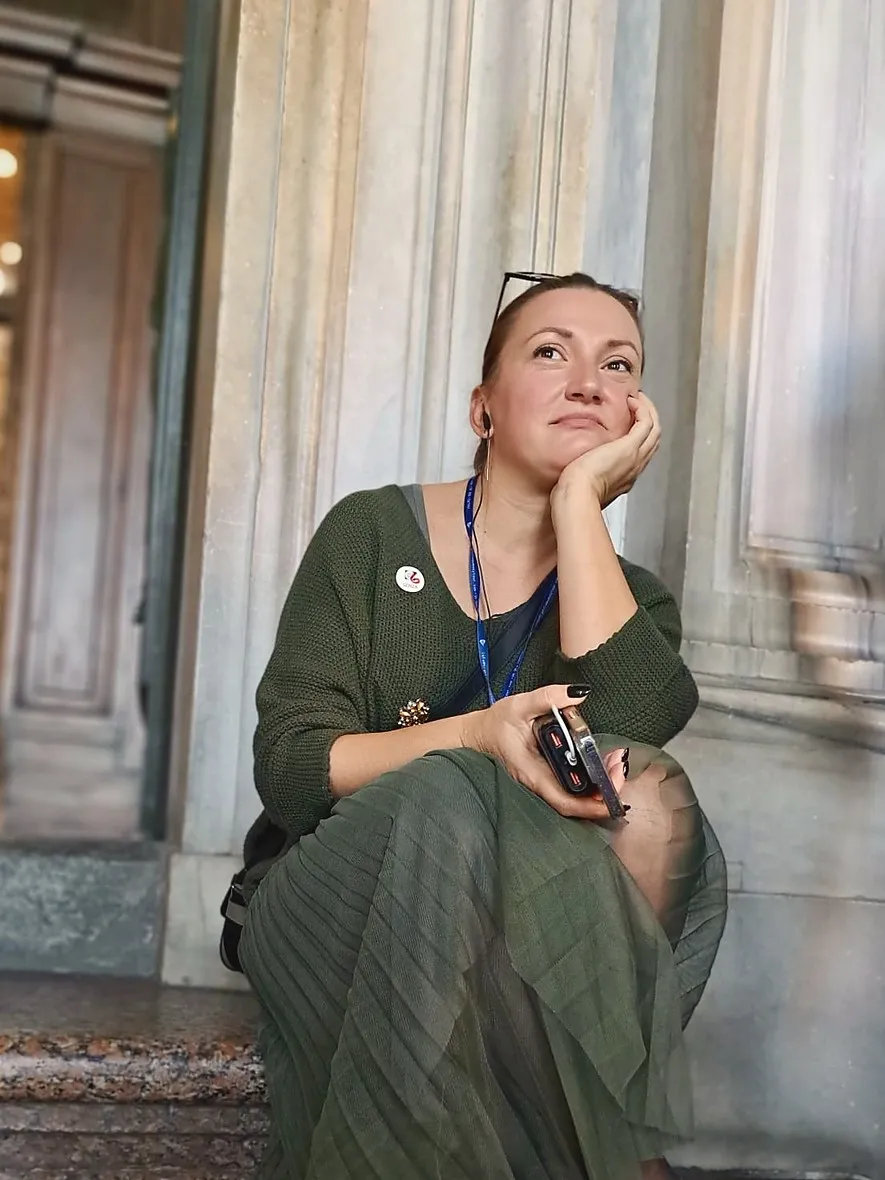 Mioara Claudia Rusu, așezată pe treptele unei clădiri, cu mâna sub bărbie